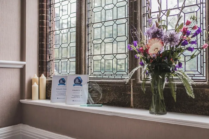 Award certificates displayed beside a vase of flowers