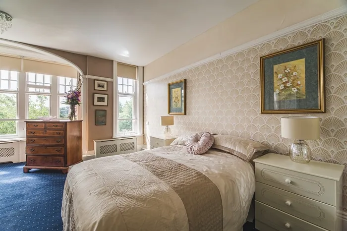 A bedroom with a floral headboard, cushions and fitted wardrobes