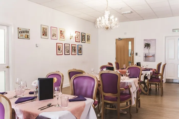 The dining room with purple chairs and framed pictures on the wall