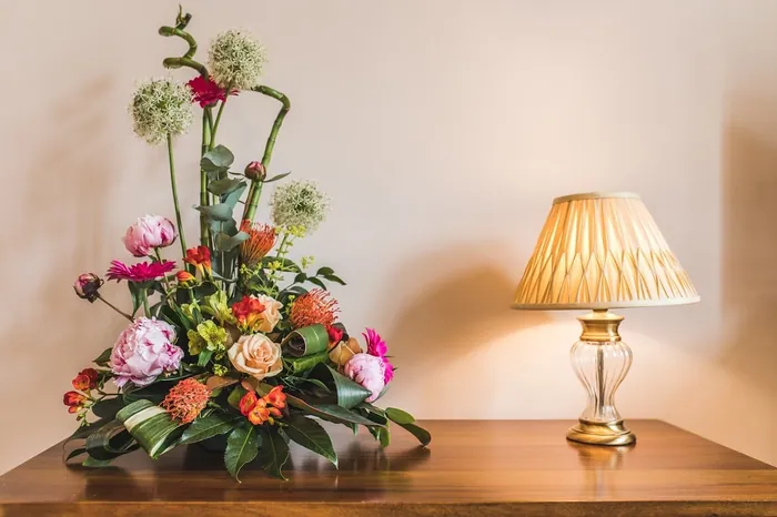 A colourful flower arrangement beside a table lamp