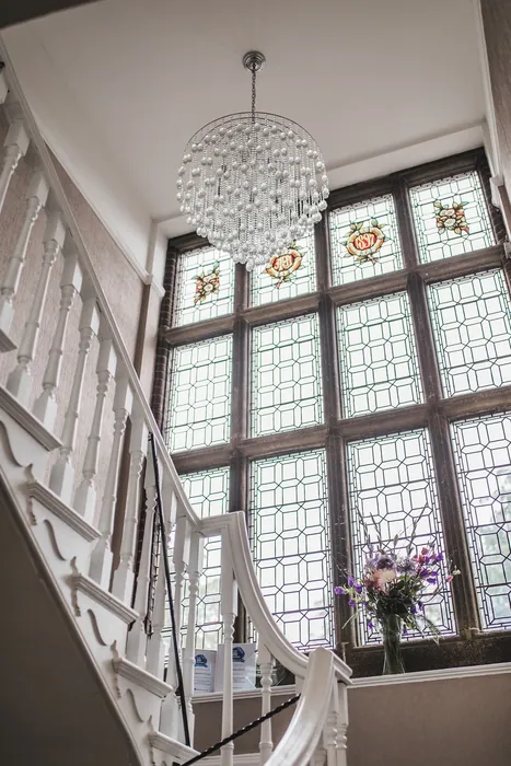 The grand staircase with stained-glass windows and a crystal chandelier